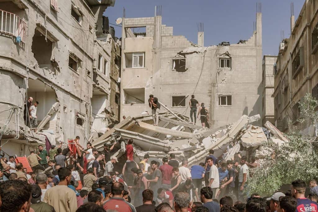People gather around a building demolished by Israeli airstrikes to rescue injured civilians and retrieve bodies from the rubble in Gaza.