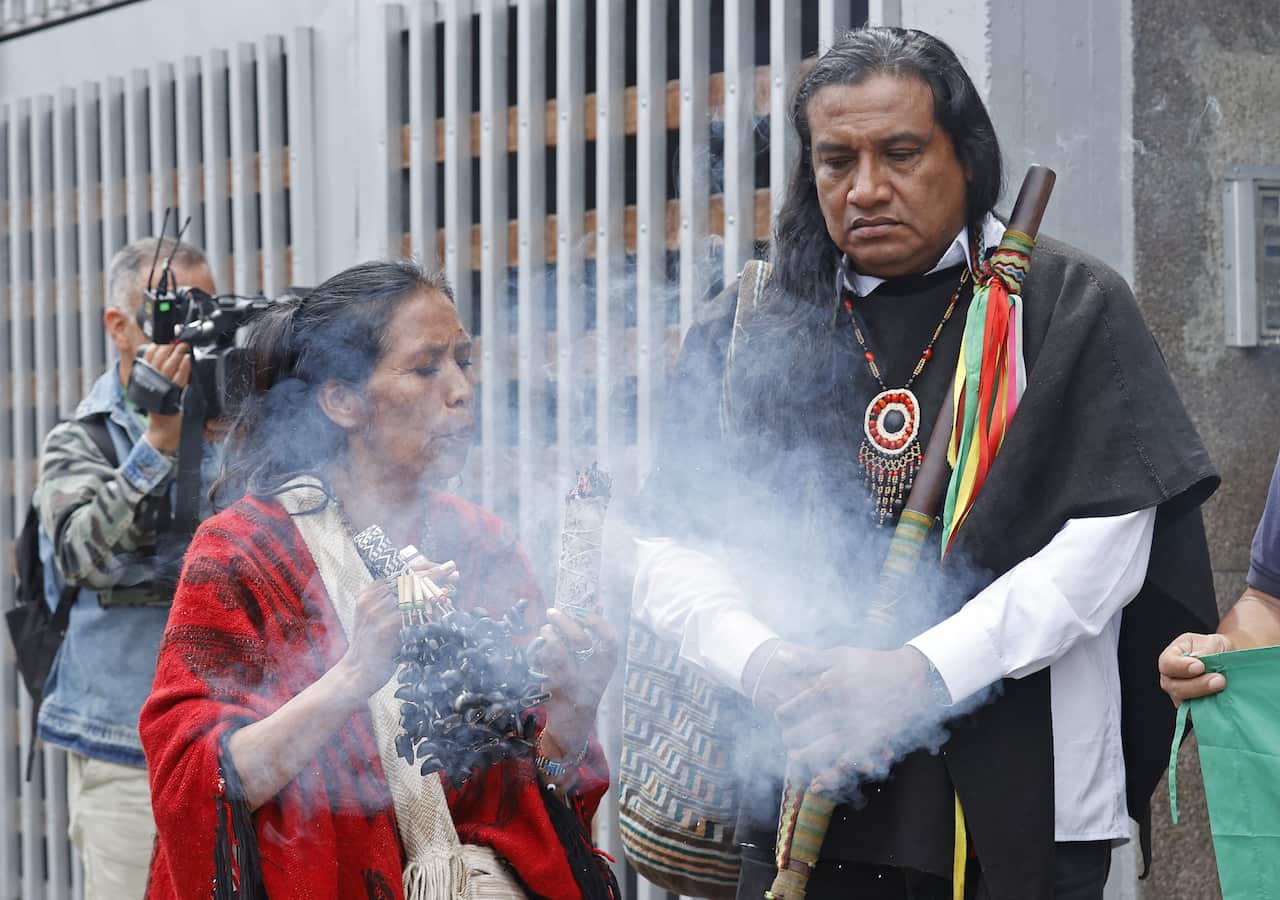 A traditional doctor performs a ritual during the press conference of Luis Acosta (right), coordinator of the Indigenous guard in charge of searching for the children lost in the Amazon jungle. 