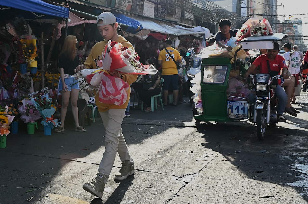 A person walking along a street holding a bunch of flowers.