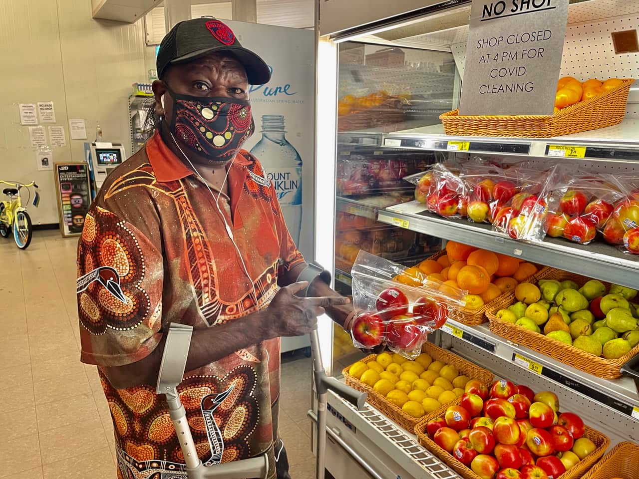 A man standing in front of a fresh fruit display in a supermarket.