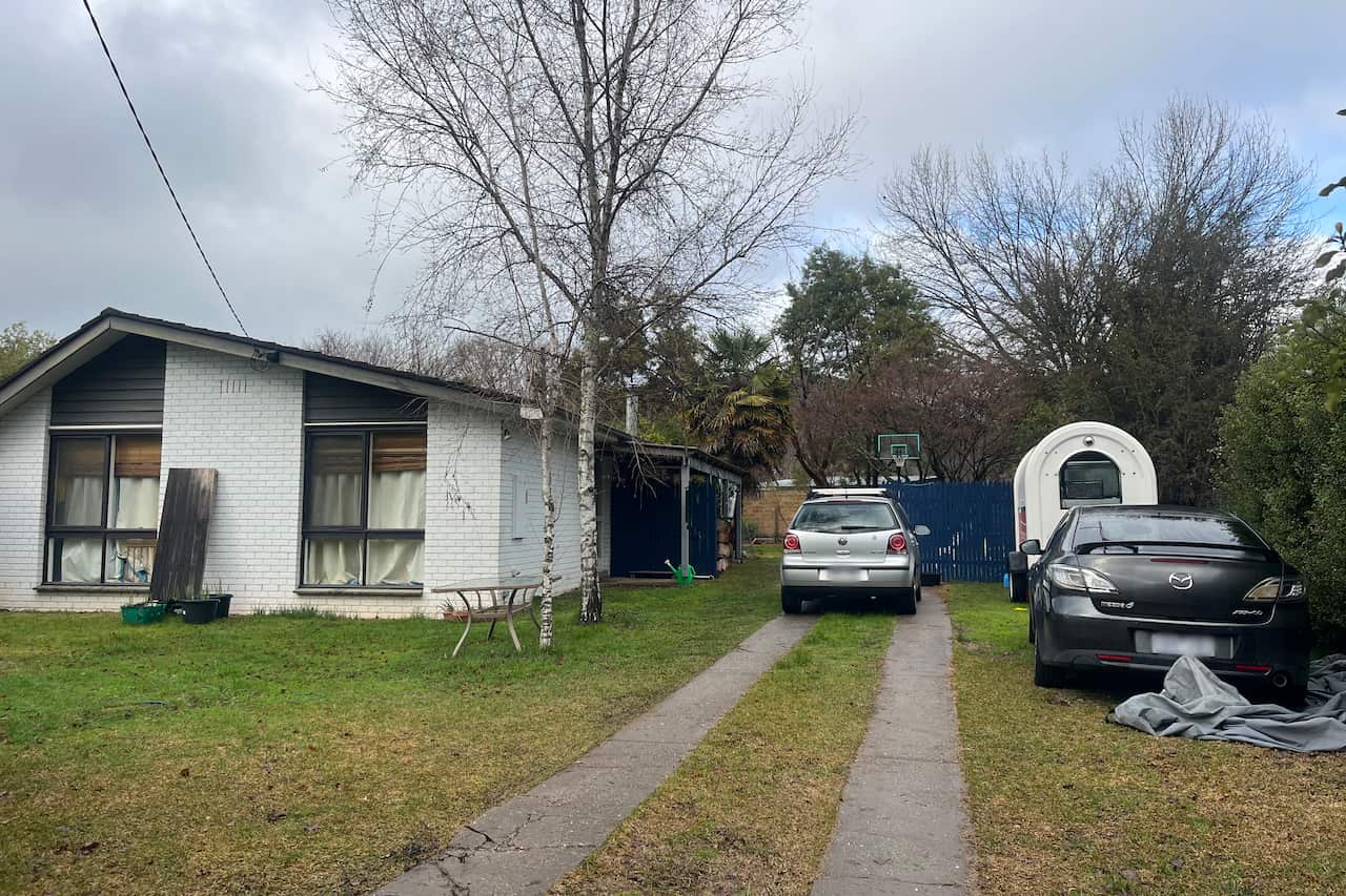 A white house, with two vehicles parked on the lawn near it.