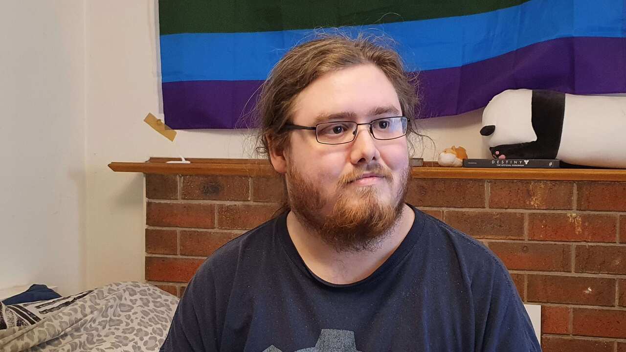 Man wearing glasses sitting on a bed