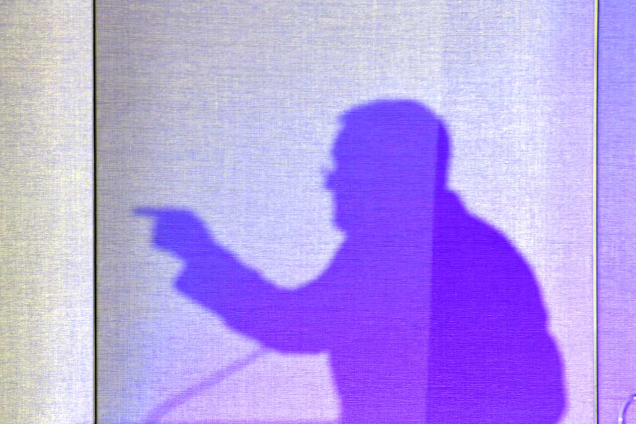 Scott Morrison's silhouette casts a shadow on a screen as he gives a talk.