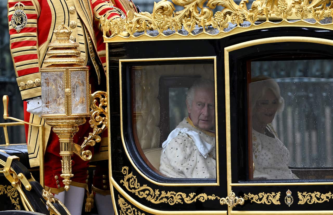 King Charles and Queen Consort Camilla are seen through the window of a coach.