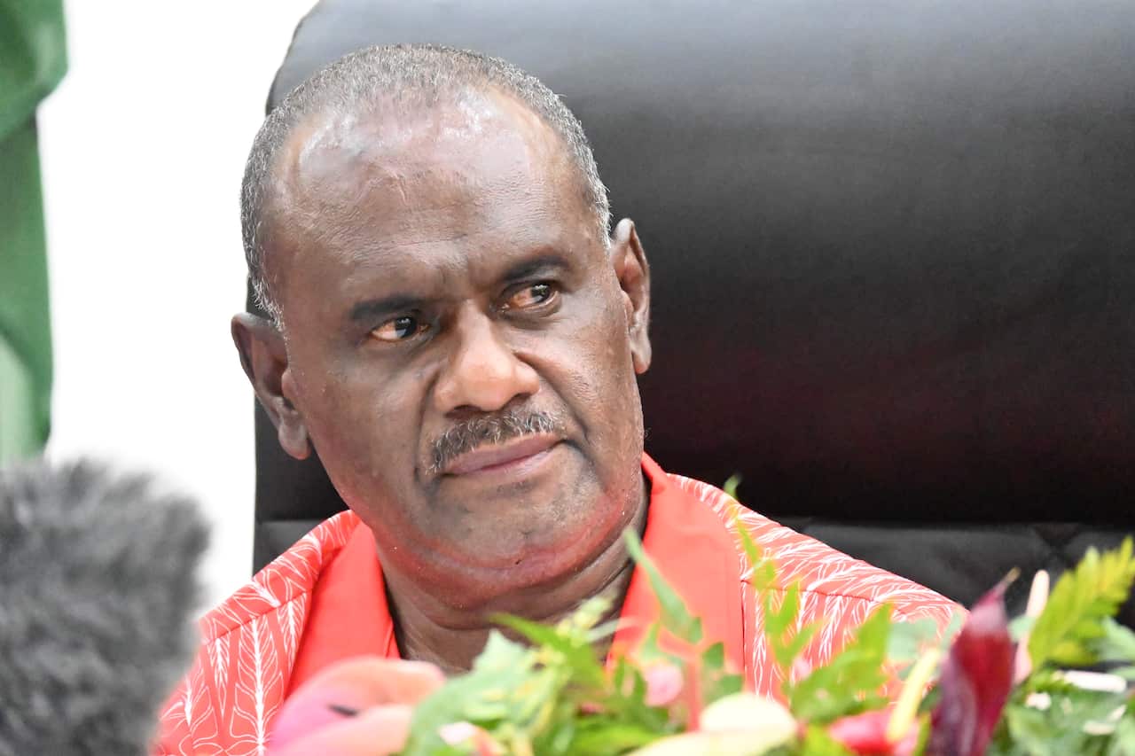 A man in an orange t-shirt is sitting.