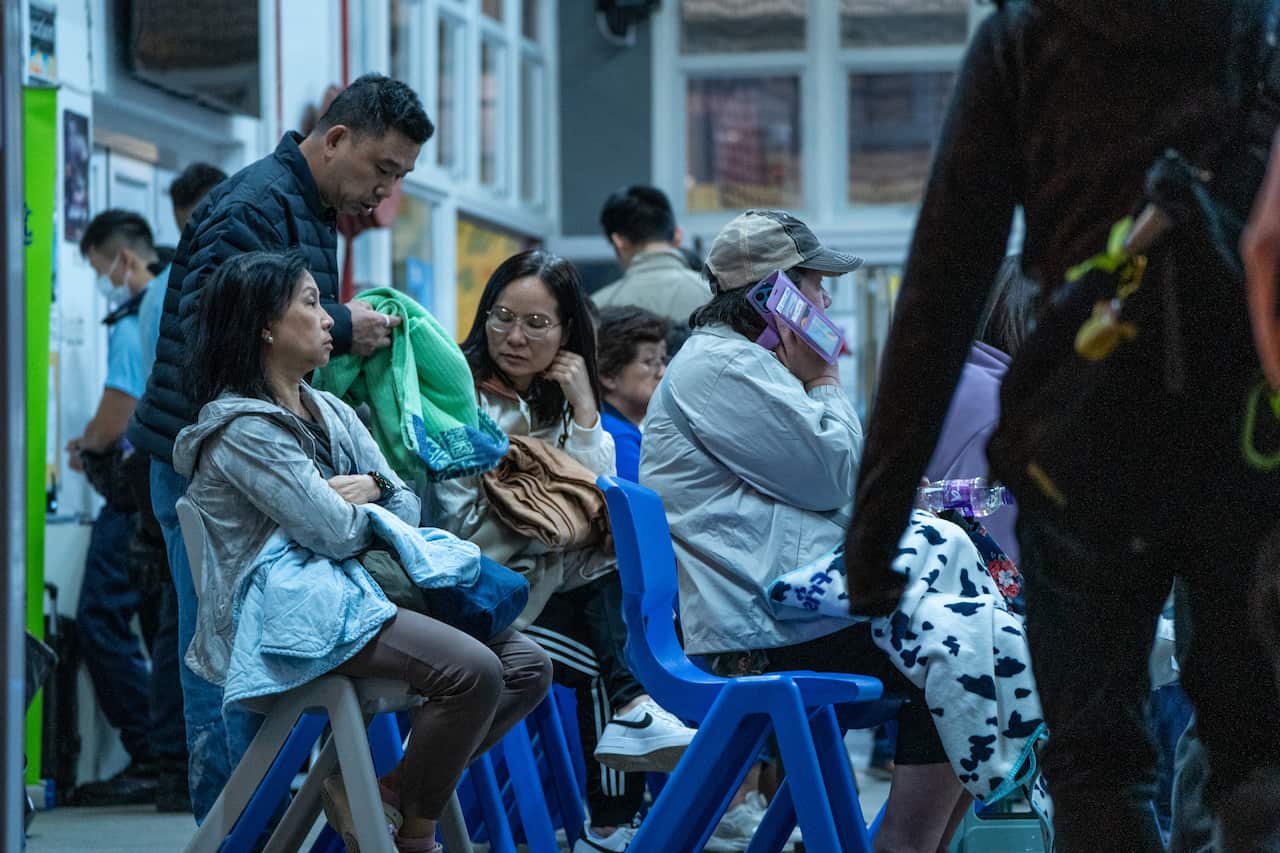 A group of people sitting on plastic chairs.