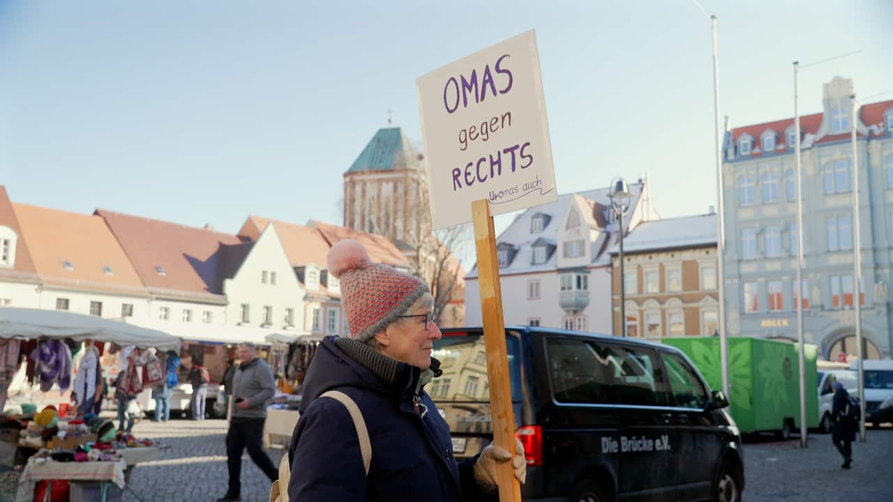 A woman in a beanie holding a sign that says Omas Gegen Rechts