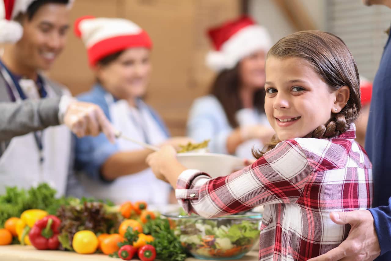 Multi-ethnic group of volunteers serves food at soup kitchen.