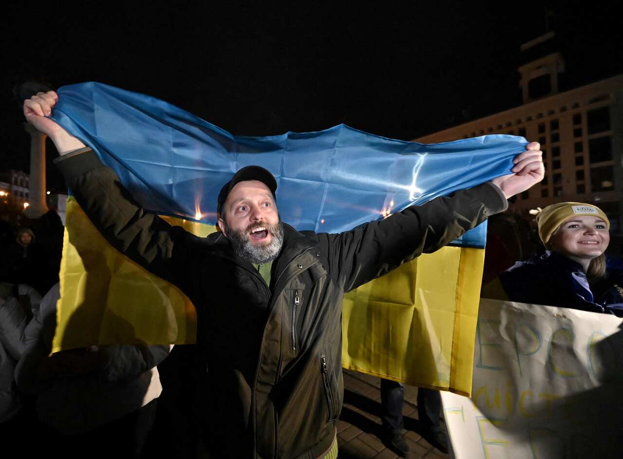 A man holds a Ukranian flag as people gather in Kyiv's Maidan Square to celebrate the recapture of Kherson. 