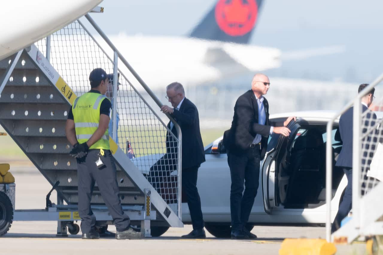 Anthony Albanese climbing up the stairs to a plane on a tarmac.