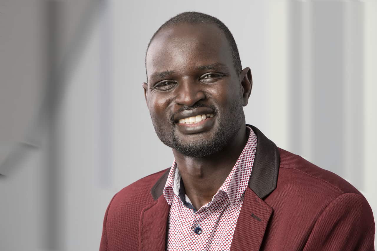 A man wearing a suit smiles for a photo. 