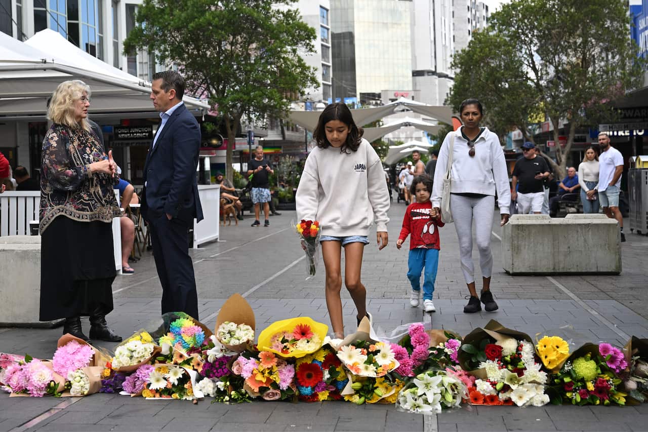 People lay flower tributes in a street.