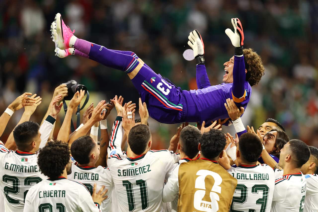 A goalkeeper being lifted into the air by his teammates 