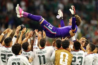 A goalkeeper being lifted into the air by his teammates