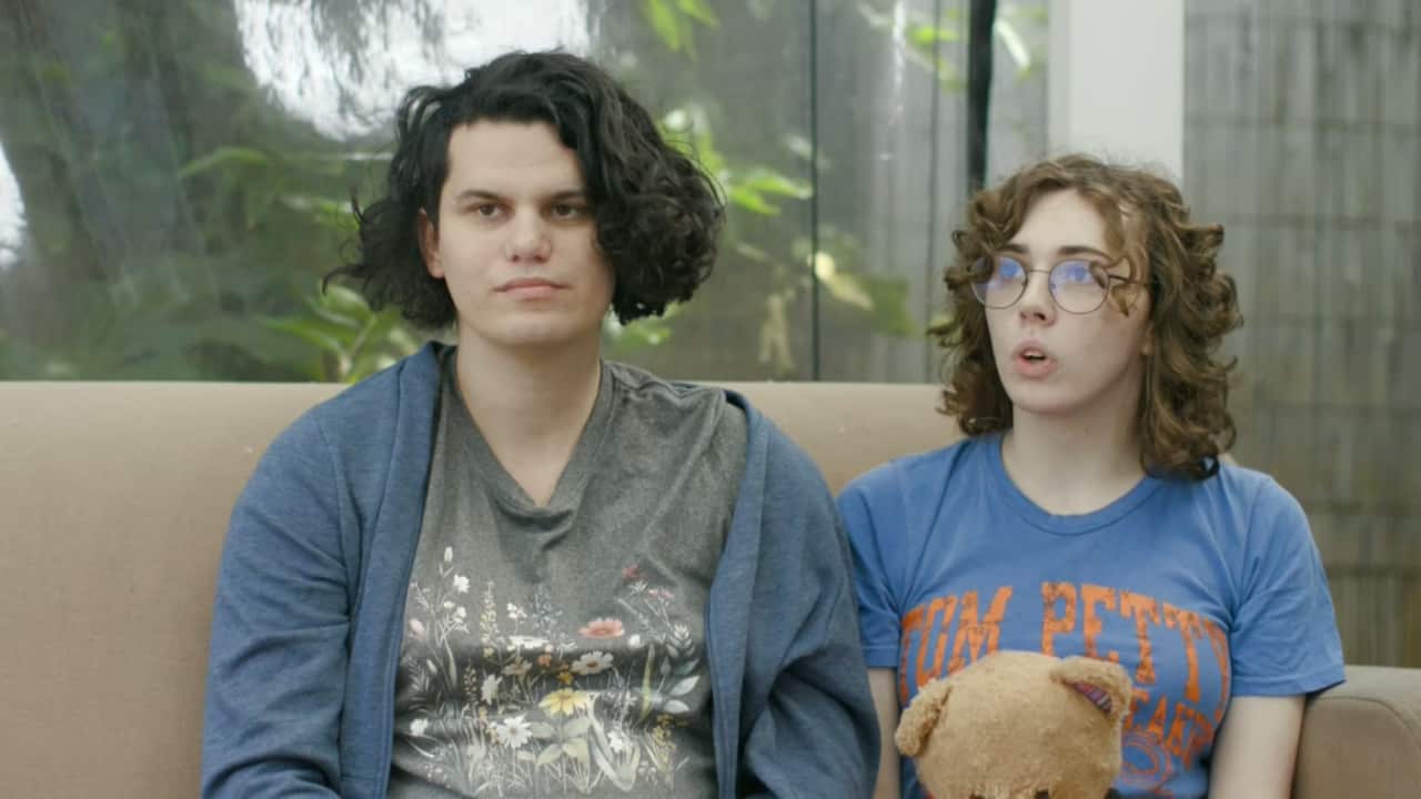 Two women speaking while seated on a couch.
