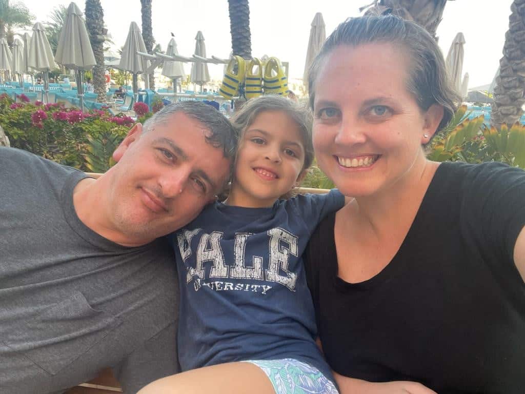 A man and woman with their child in between, all smiling.