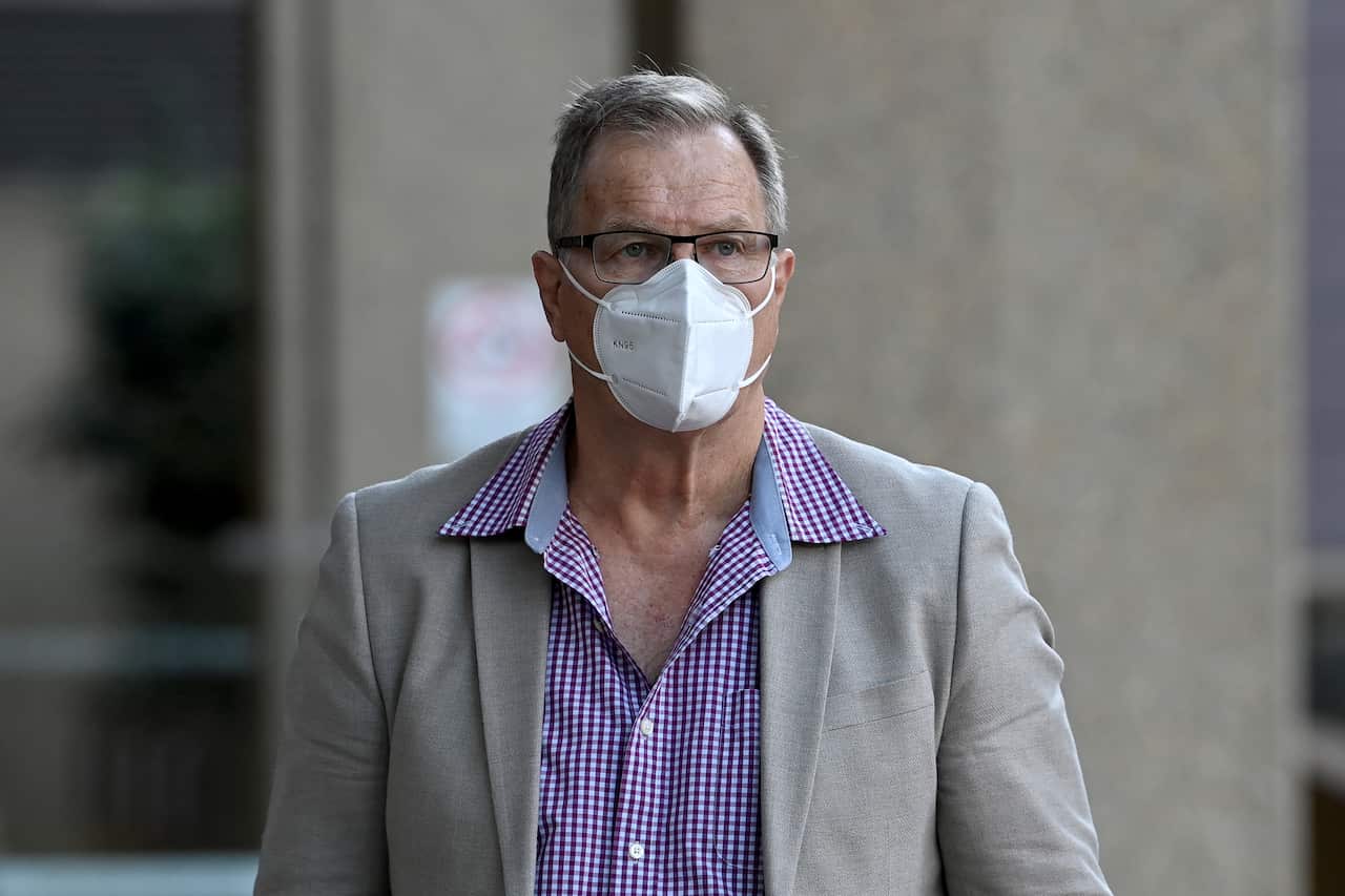 A man wearing a shirt, blazer and face mask.