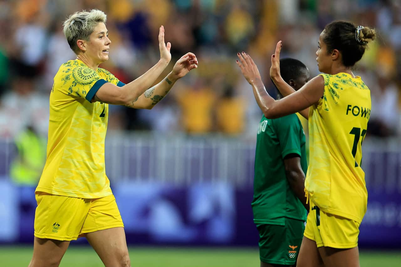 Two female footballers in yellow uniforms celebrate