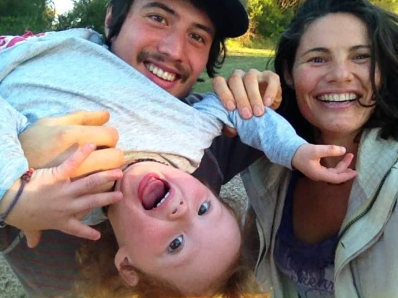 A smiling mother and father hold their happy child upside down.