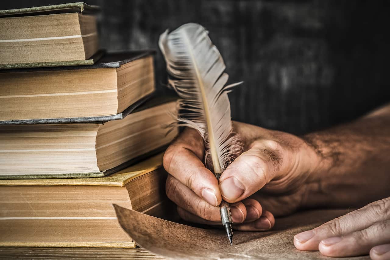  Old quill pen, books and papyrus scroll on the table. 