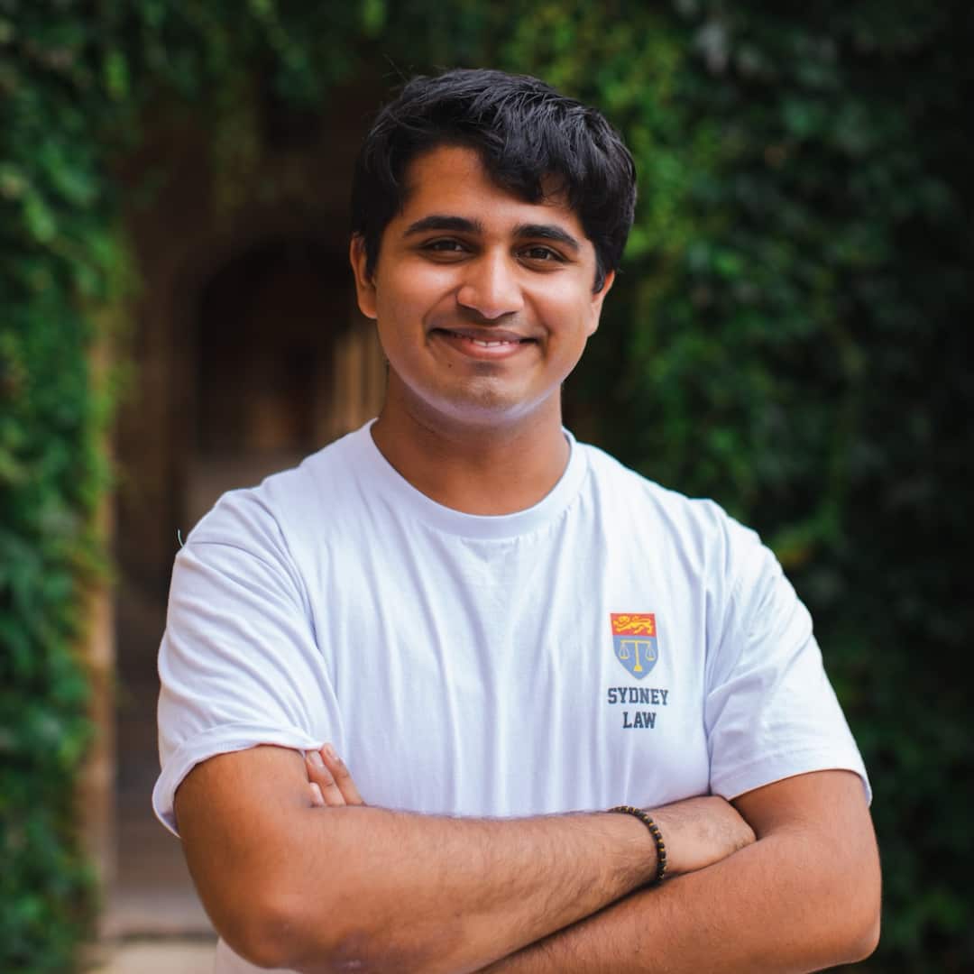 A man with brown hair in a white university t-shirt. 