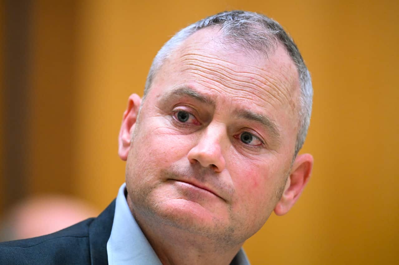 A man with grey hair looks sideways. 