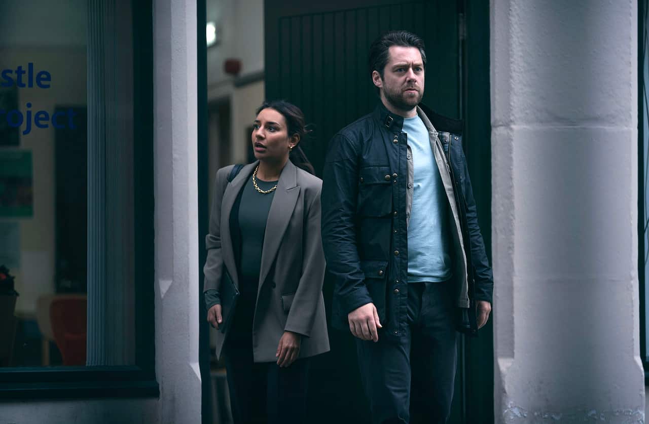 A man and a woman walk out of a building. She has a suprised look on her face. 