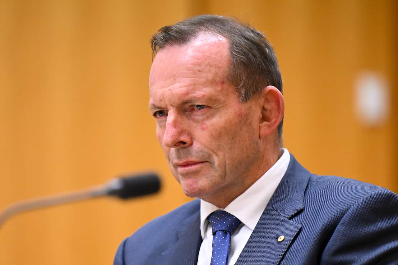 Man in suit and tie speaks in front of a microphone.