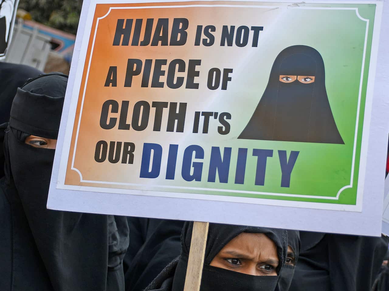 A Muslim woman wearing a hijab holds a placard during a protest