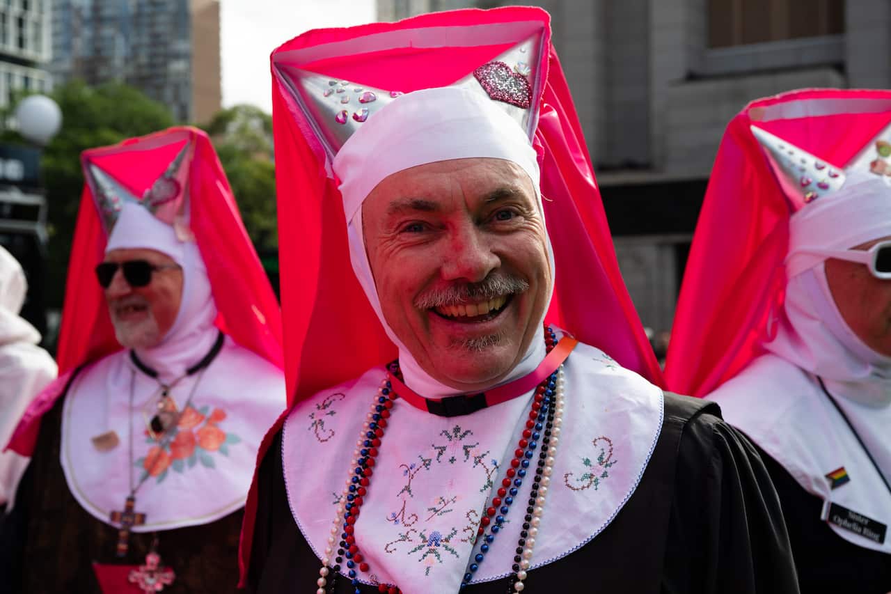 A man in a pink medieval hat smiles at the camera.