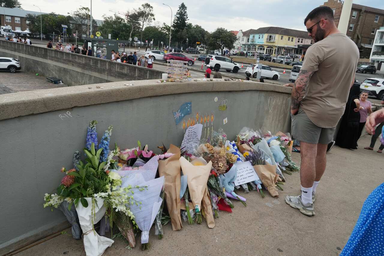 A man looks at a flower tribute on the bridge at Bondi Beach in Sydney