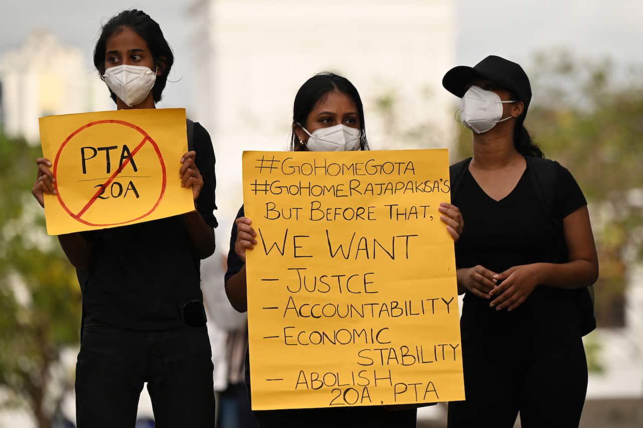 Three protesters are seen. Two are holding placards.