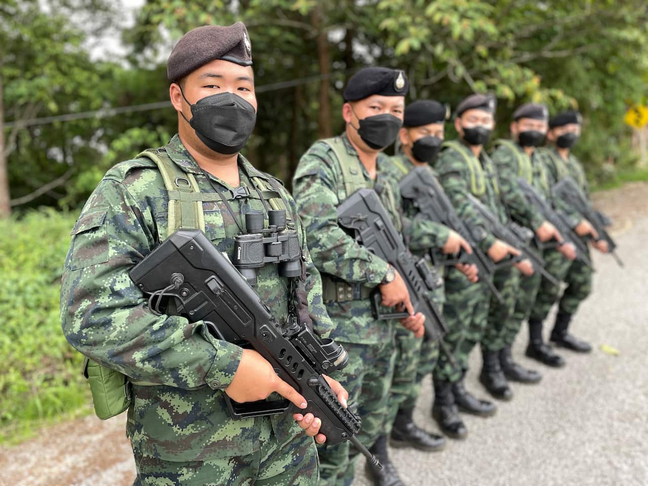 A line of soldiers wearing camouflage uniforms and holding guns.