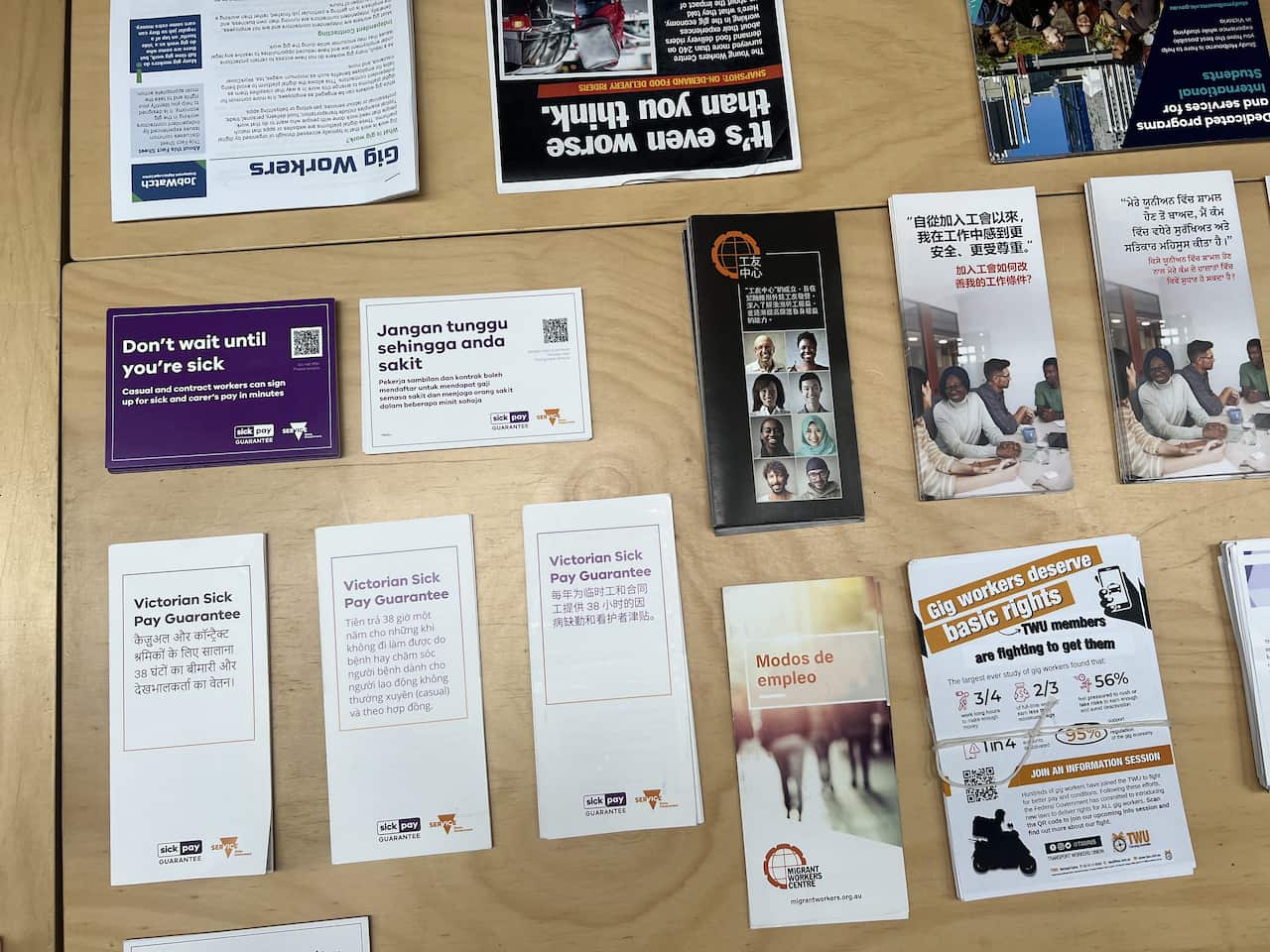 Pamphlets in several languages neatly placed across a wooden table