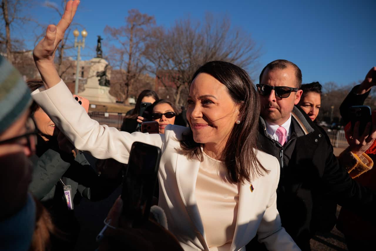 A middle-aged Latino woman waving to her supporters as she walks through a crowd.