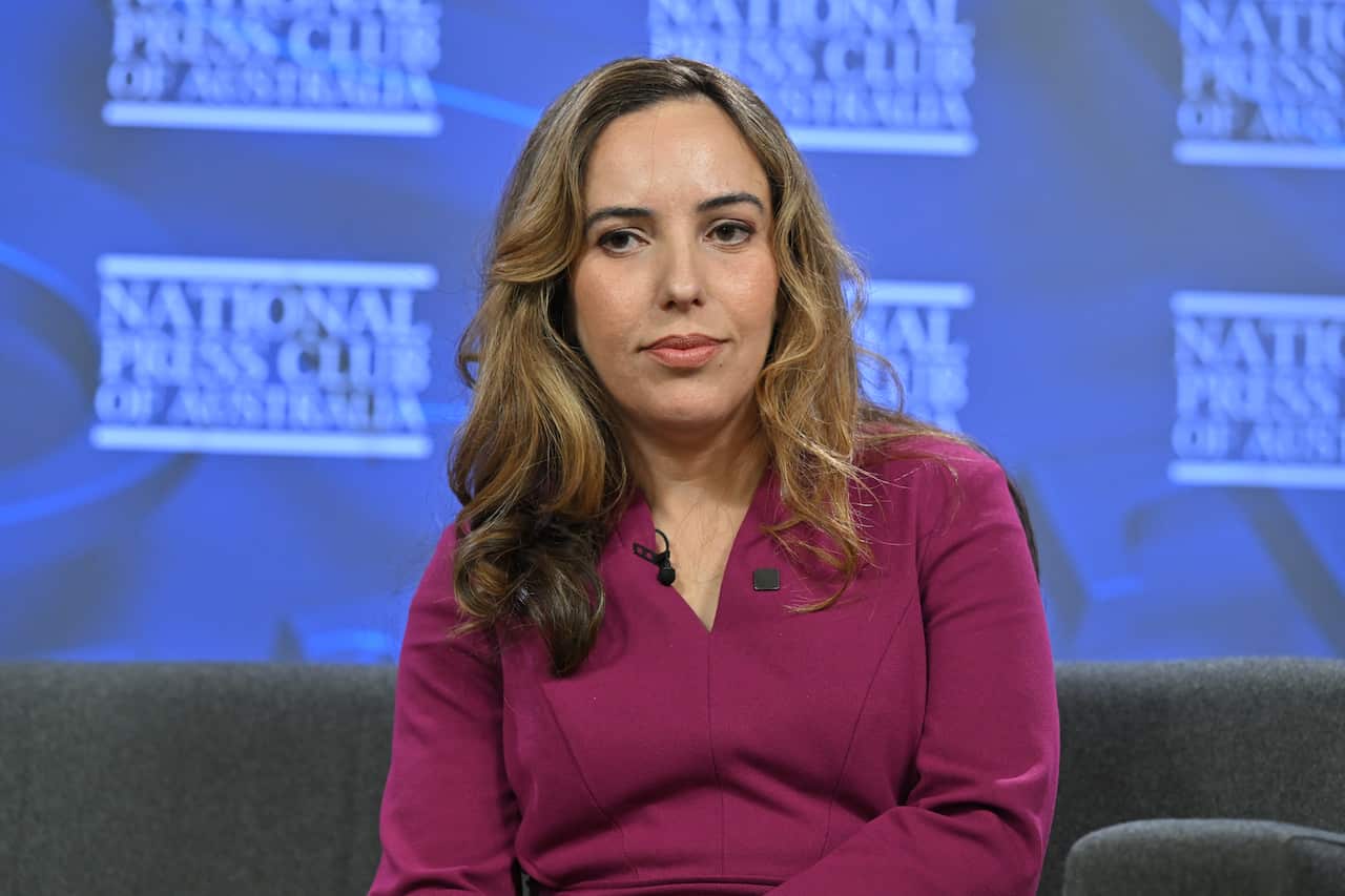Woman in purple dress sits on couch.