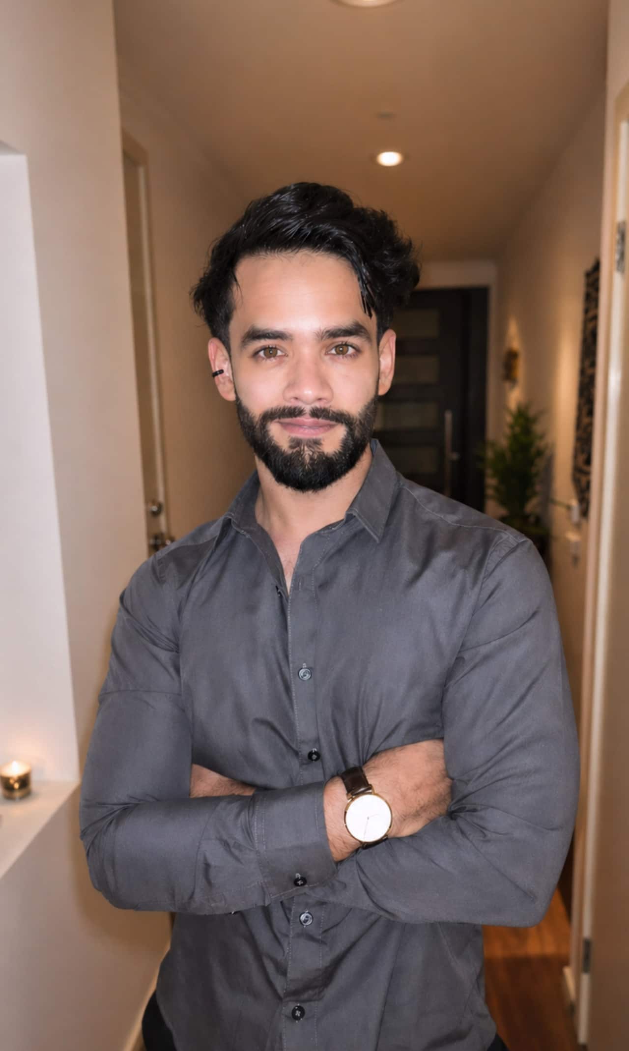 Bashshar Khalid stands indoors with his arms crossed, wearing a grey button-up shirt.