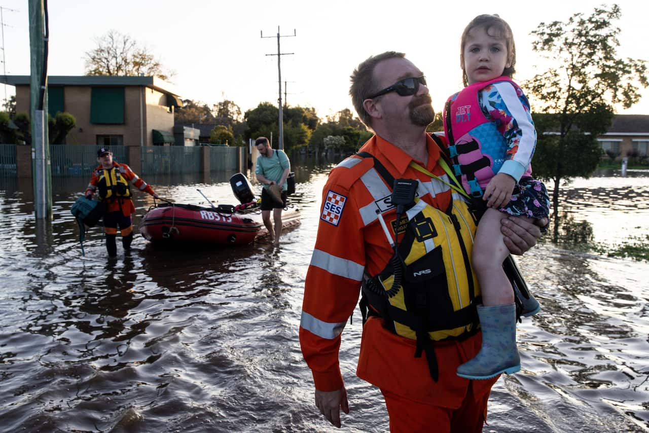 SES personnel carry a child through floodwaters