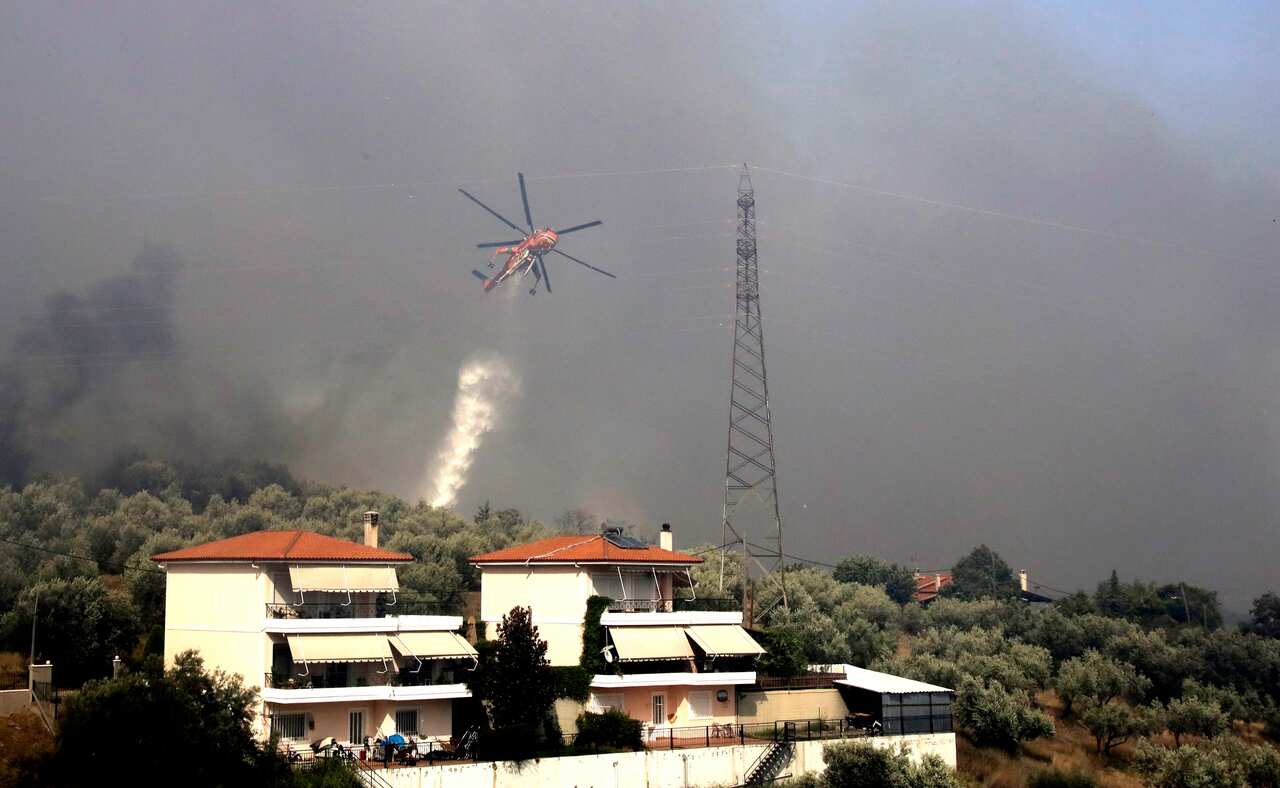 A firefighting helicopter drops water on a fire.