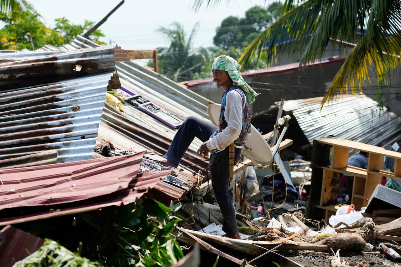 A man walking over damaged buildings after a landslide