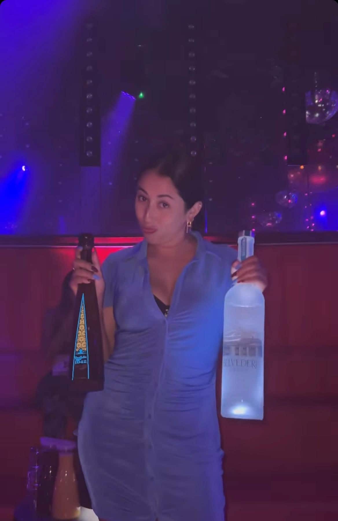 A woman holding two bottles of alcohol.