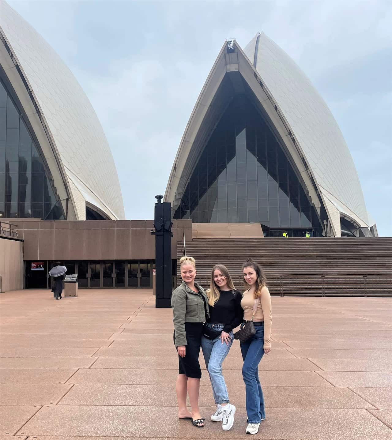 Jasmine Straga (left) with Vlada and Mariia stand in front of the Sydney Opera House  