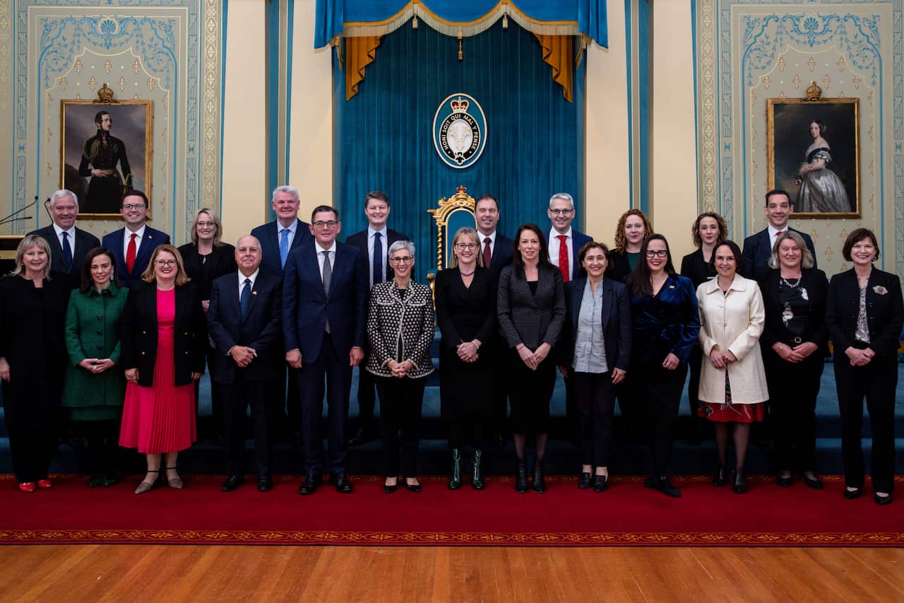Men and women wearing formal attire standing and posing for a photo.