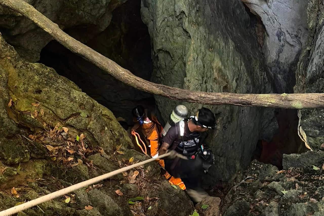 A man rappelling down into a dark cave.