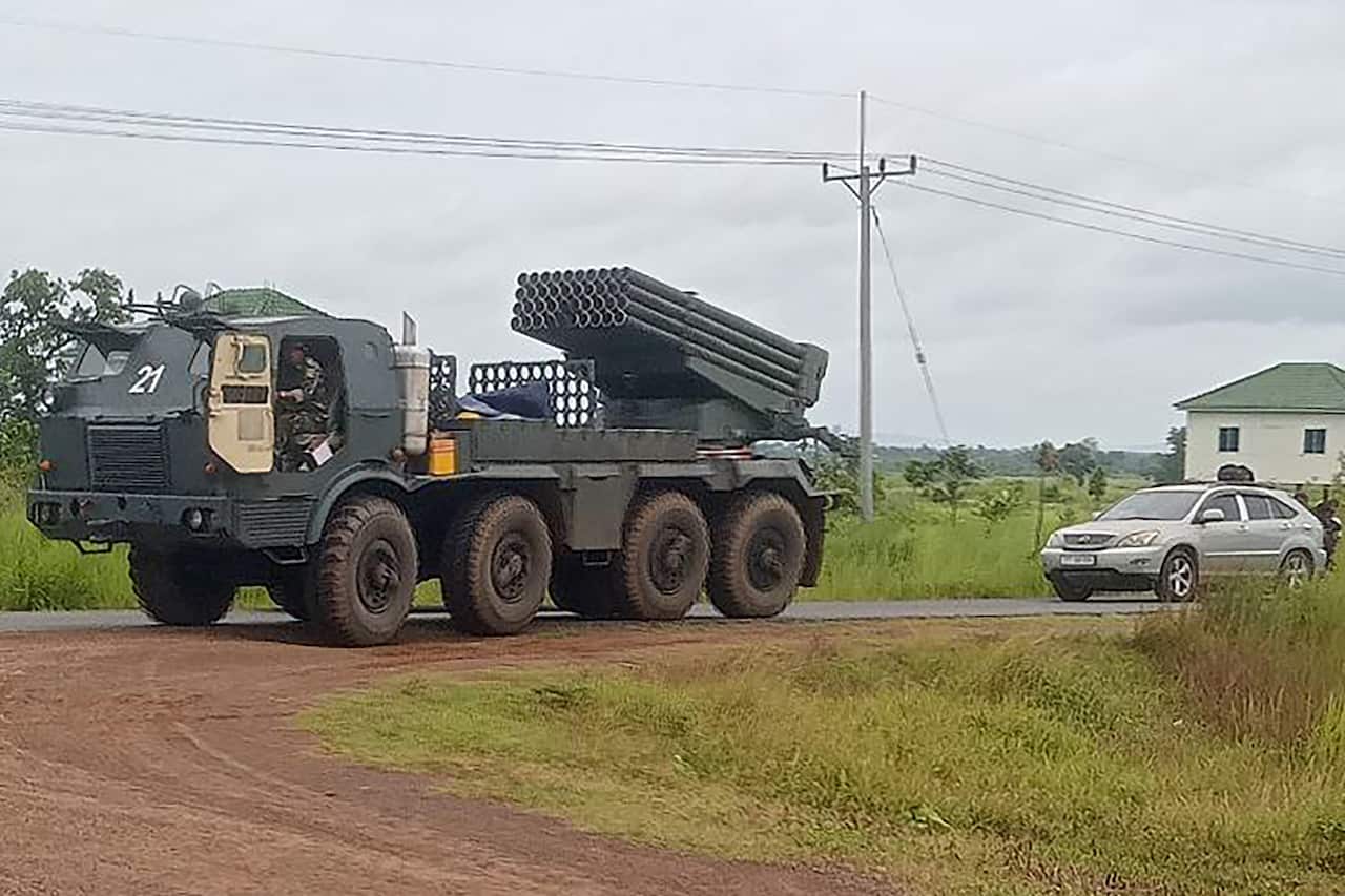 A large vehicle with a rocket launcher driving on a dirt road.