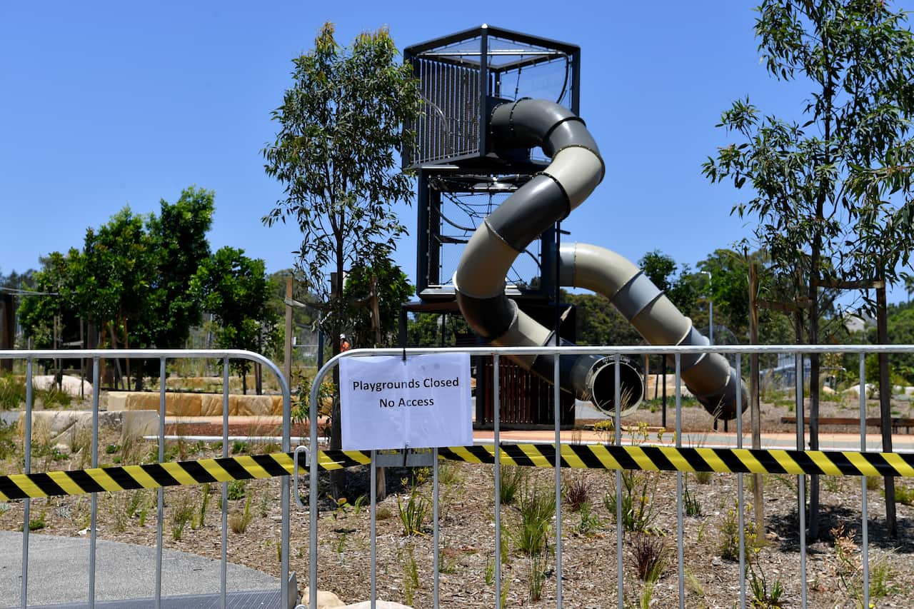 A playground with a barrier in front of it and a sign that reads 'Playgrounds Closed No Access'.