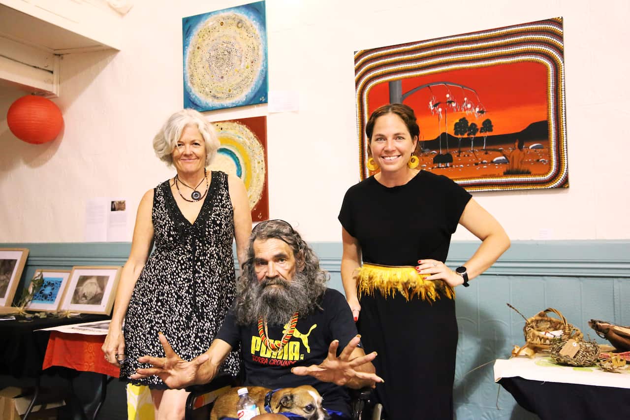 A middle-aged woman with her father, who is in a wheelchair, and her mother, who is standing beside hm.