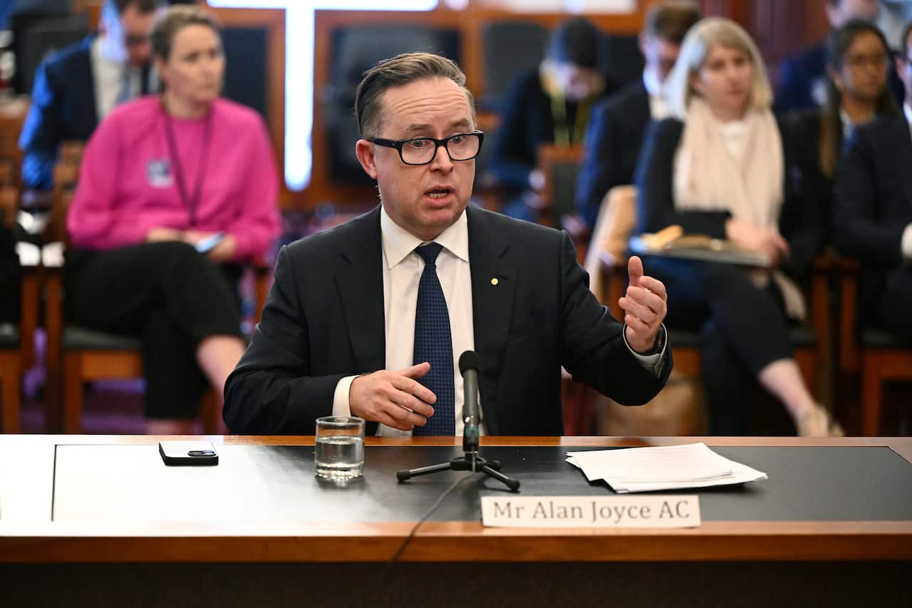 Alan Joyce sitting behind a desk with a microphone and talking