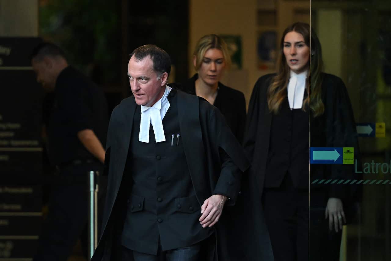 Three people exiting a building wearing professional legal attire.