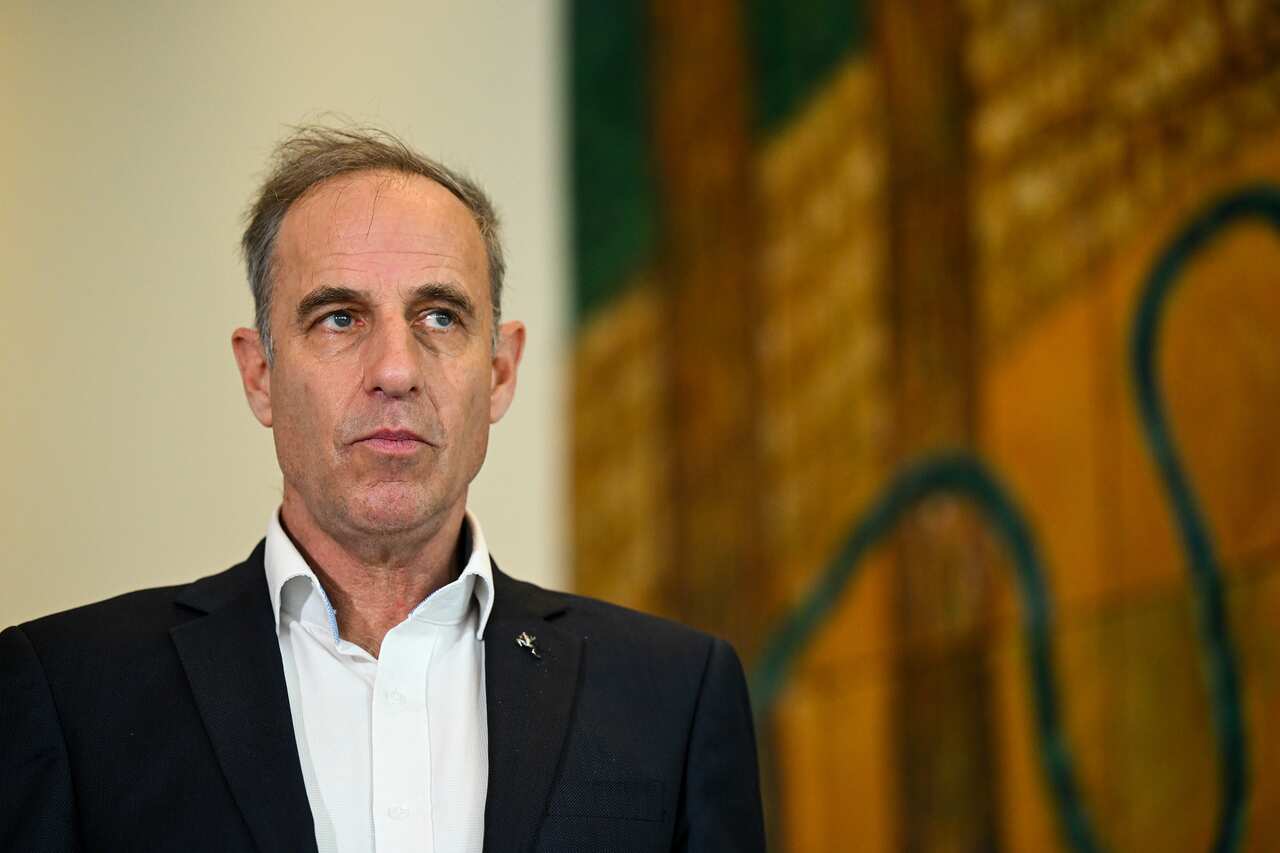 Nick McKim stands in front of a colourful yellow and green artwork.